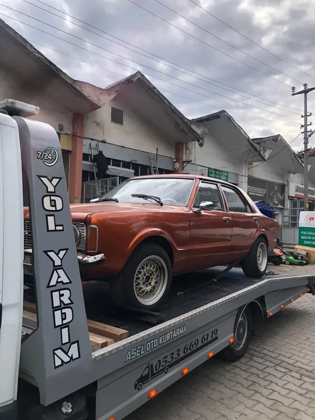Çekicinin kasasına yüklenmiş turuncu klasik otomobil, yanında Yol Yardım yazısı